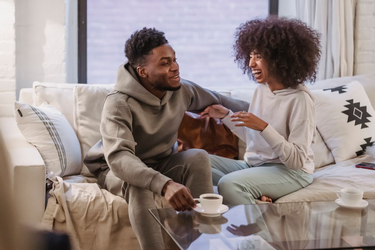 Un couple discute en souriant, assis sur un canapé