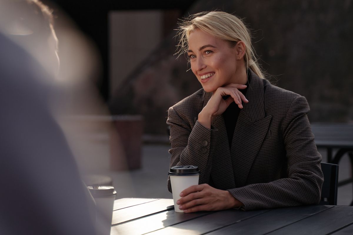 Une femme souriante, seule à une table de café