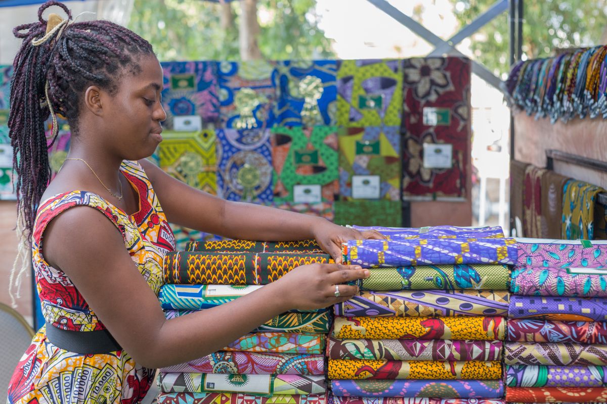 Une commerçante dispose des tissus colorés sur un marché de Cotonou