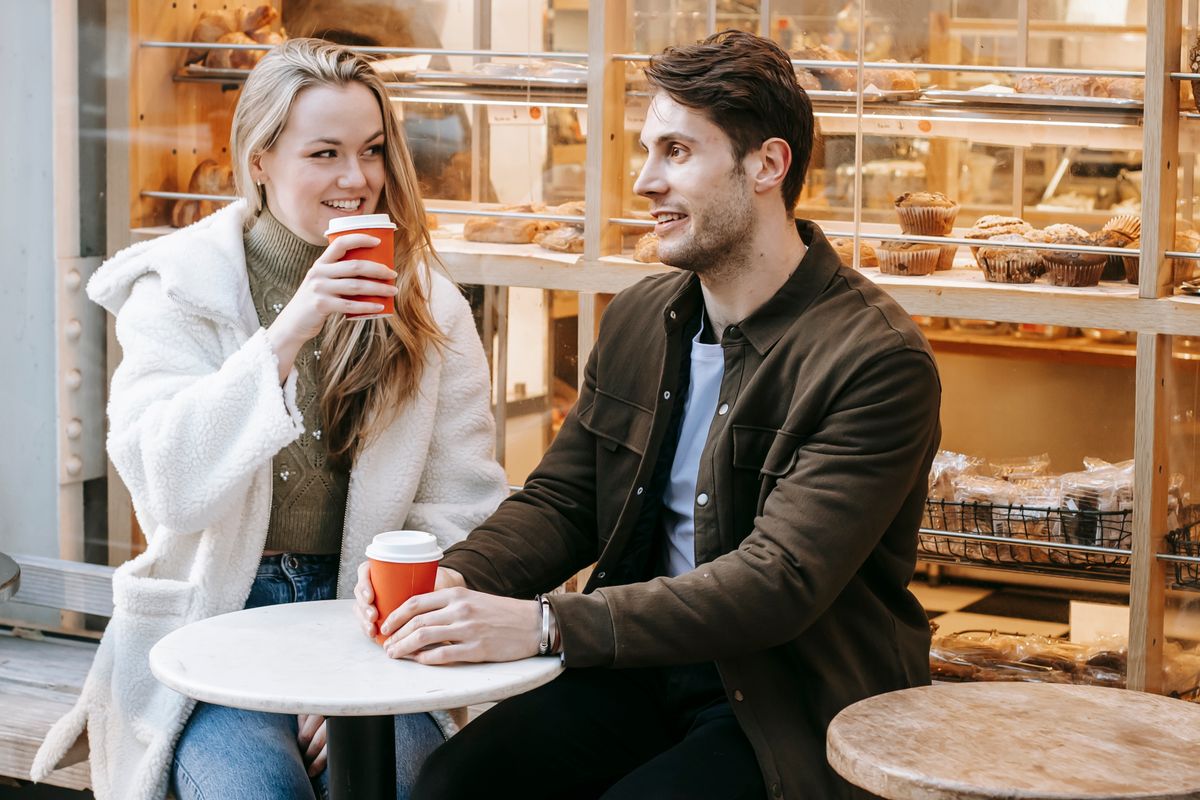 Et smilende par snakker ved et cafébord