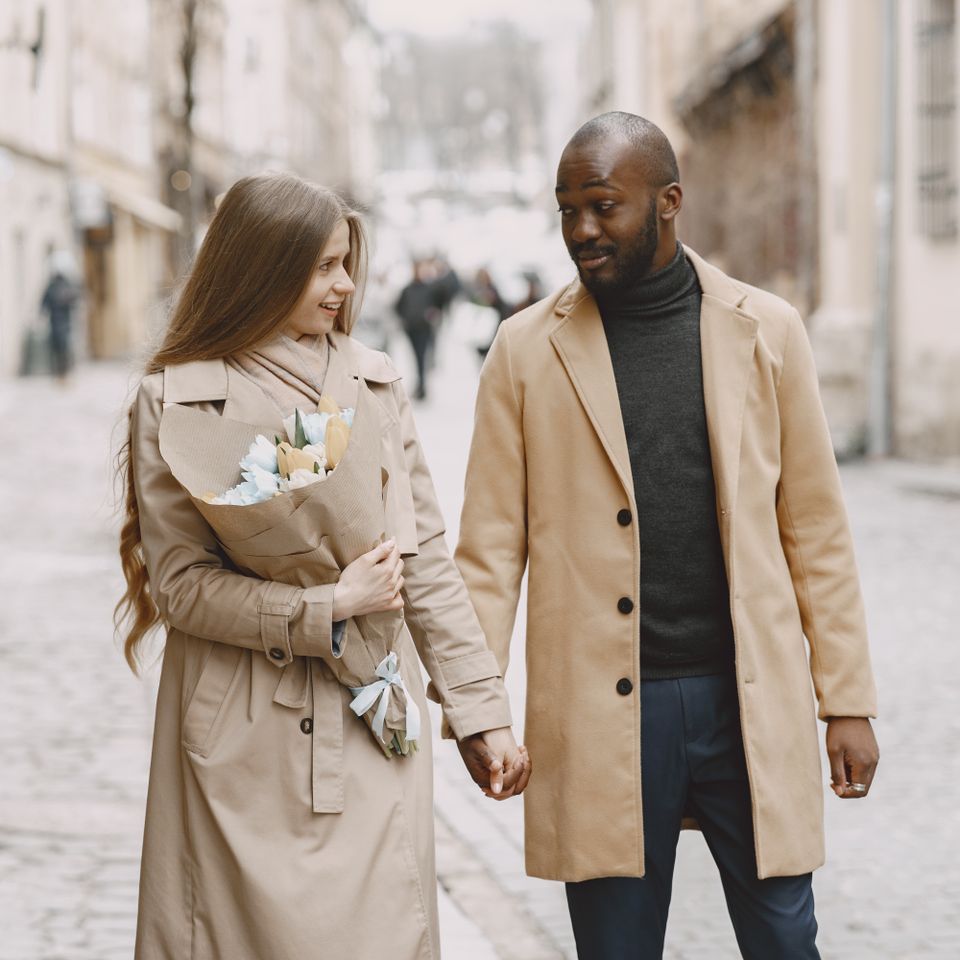 Un couple se tient la main en marchant dans une rue